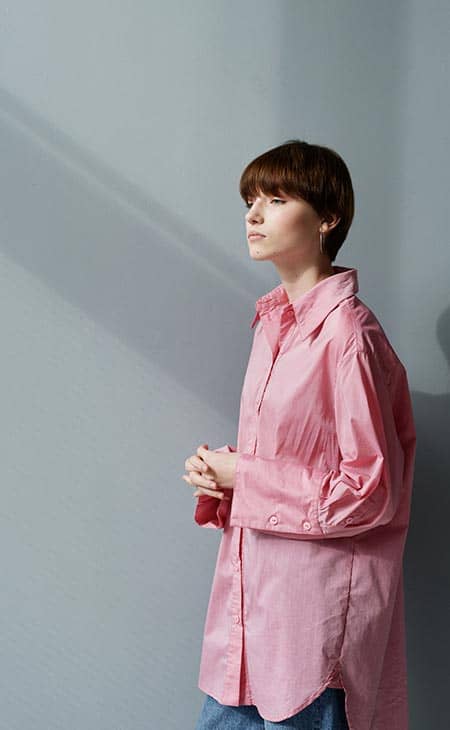 Mujer Caucasica Joven Pensativa En Camisa Rosa De Gran Tamano De Pie Con Las Manos Entrelazadas Contra Backgr Gris | How To Style An Oversized Shirt: Types, Tips &Amp; Outfit Ideas Mujer caucasica joven pensativa en camisa rosa de gran tamano de pie con las manos entrelazadas contra backgr gris