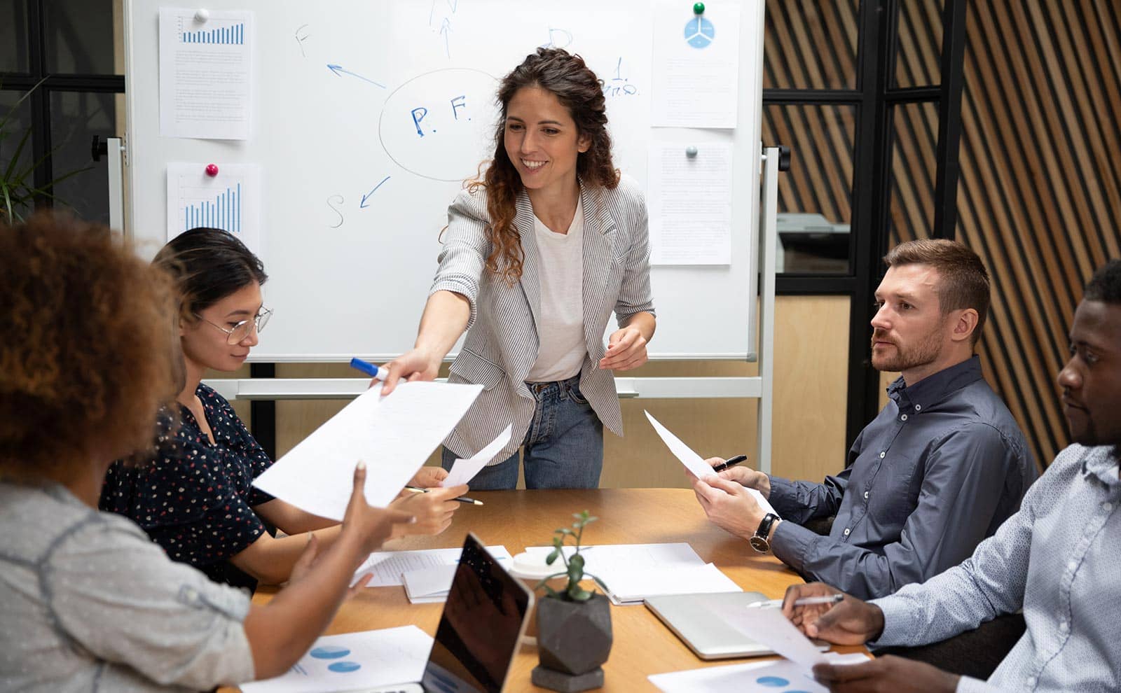 a woman in a meeting giving papers to a woman